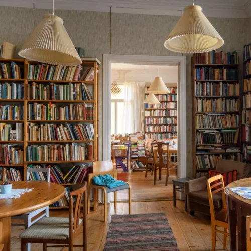 Inside the cafe of the seating area, consisting of a lot of bookcases and wooden round tables.
